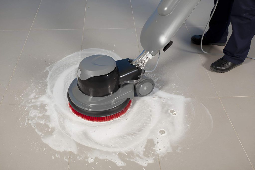 A Person Is Cleaning A Tiled Floor With A Machine — Dryology Carpet Cleaning in Newcastle, NSW