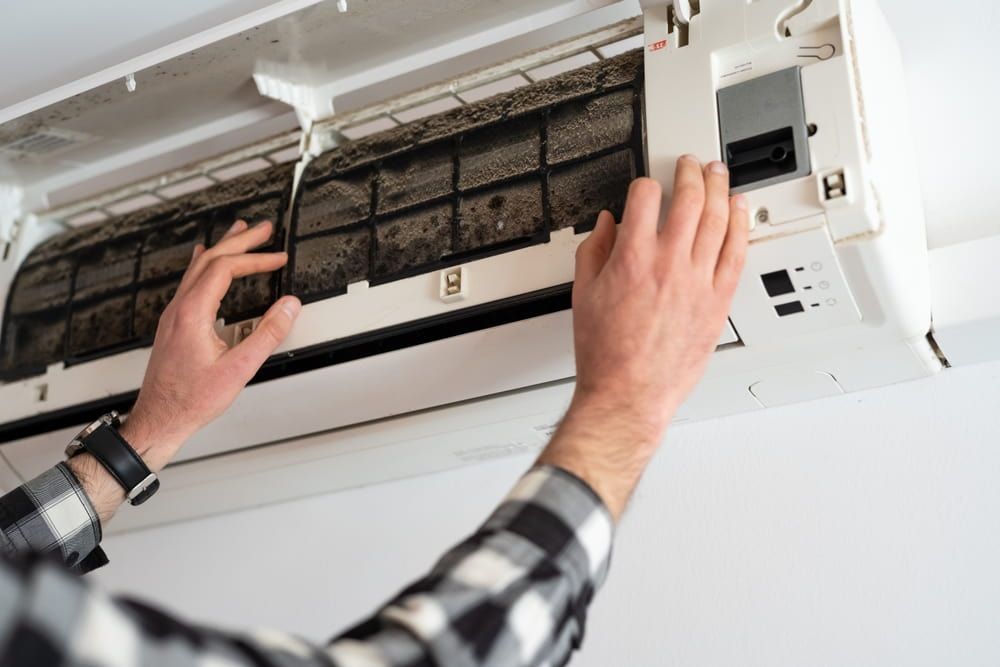 A man is cleaning the filter of an air conditioner — Dryology Carpet Cleaning in Sydney, NSW